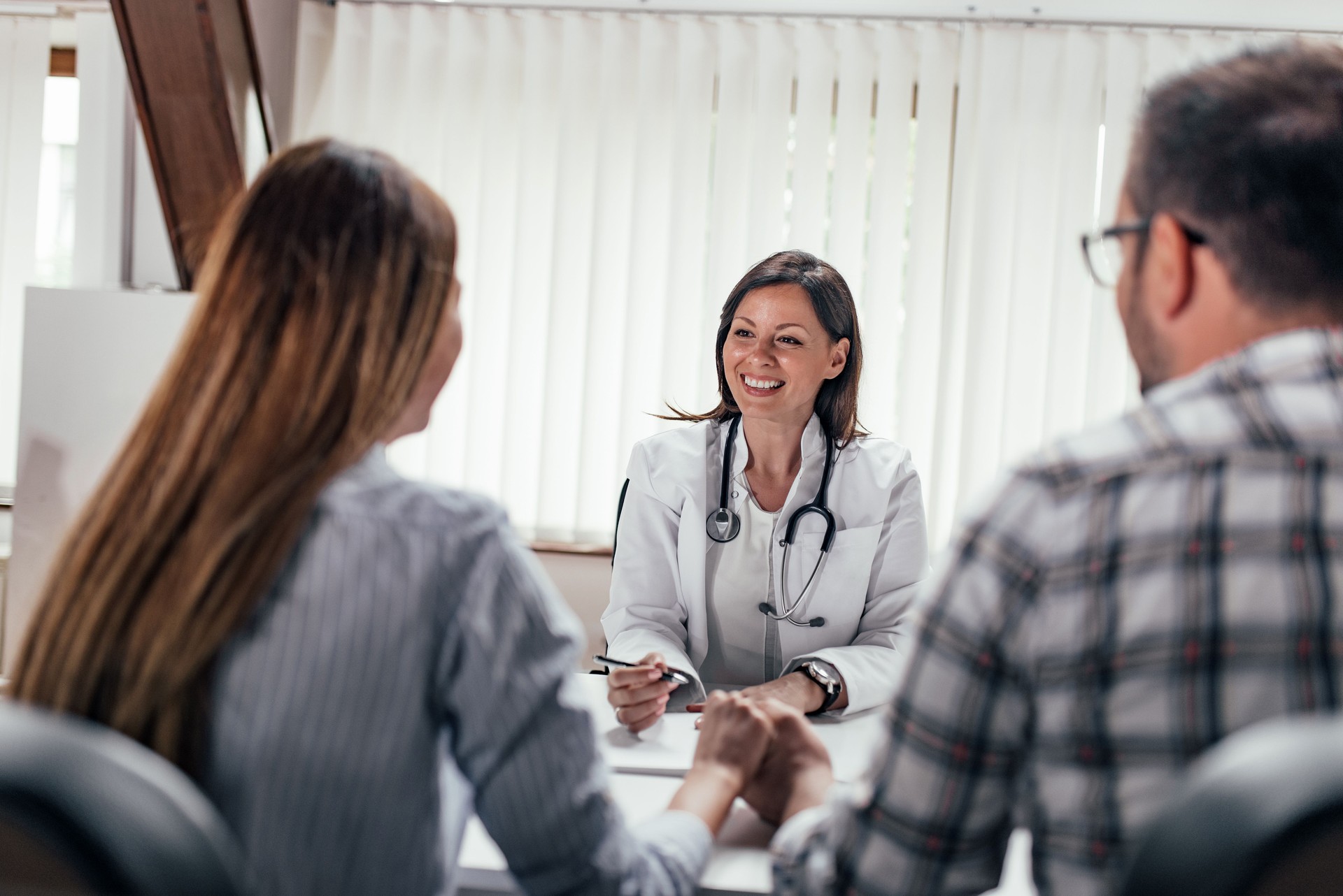 Front image of female doctor having a consultation with a couple.